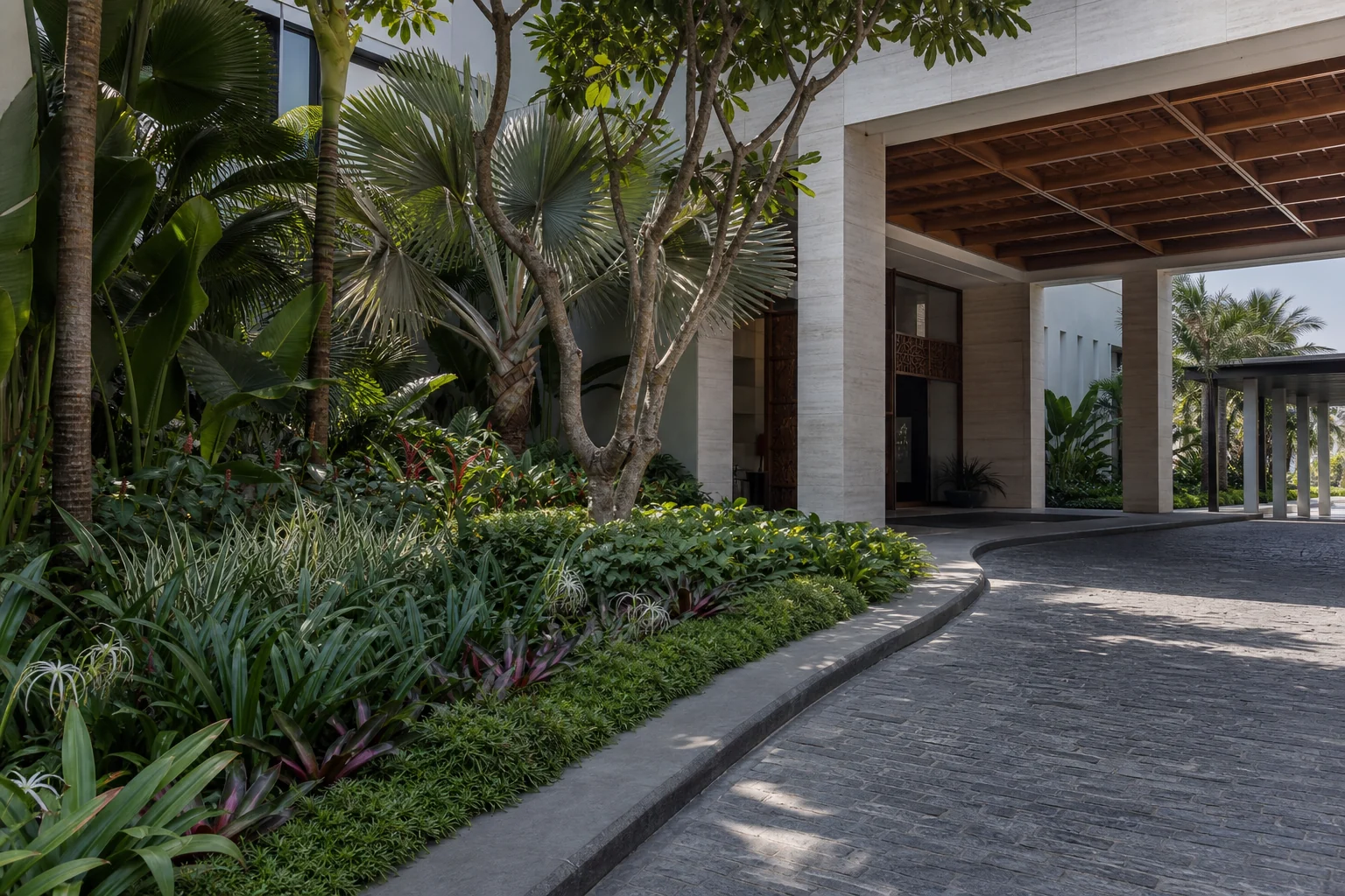 Commercial softscape with layered shrubs, palms, and a curved garden path for hospitality and campus landscapes.